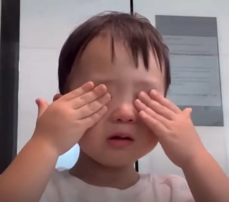 눈을 가리고 울고 있는 남자 아이의 모습
